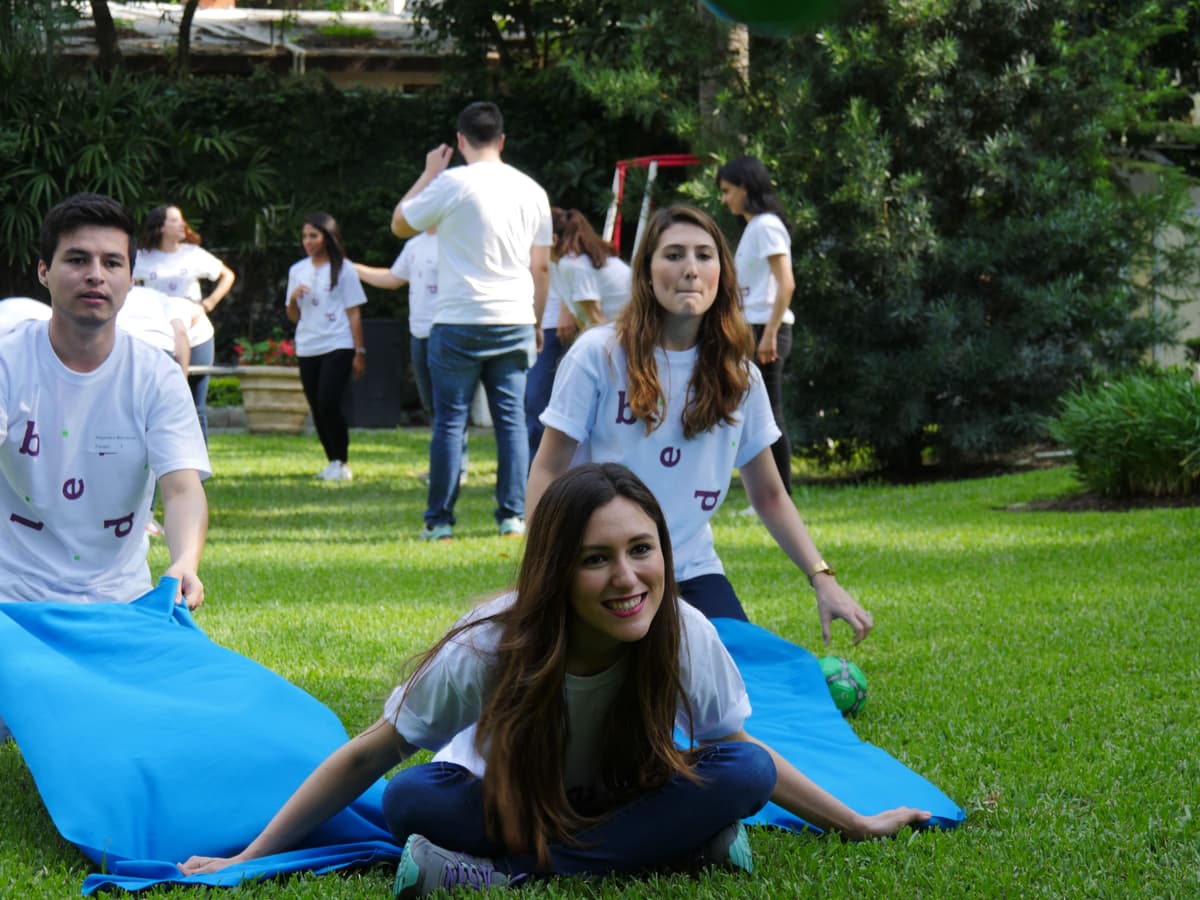 Grupo reunido en un espacio verde, colaborando para superar un desafío físico como parte del rally